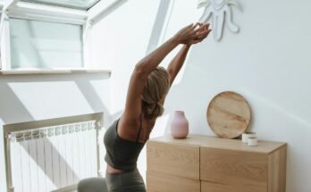 Woman doing a full-body home workout on a yoga mat in her living room with natural light.
